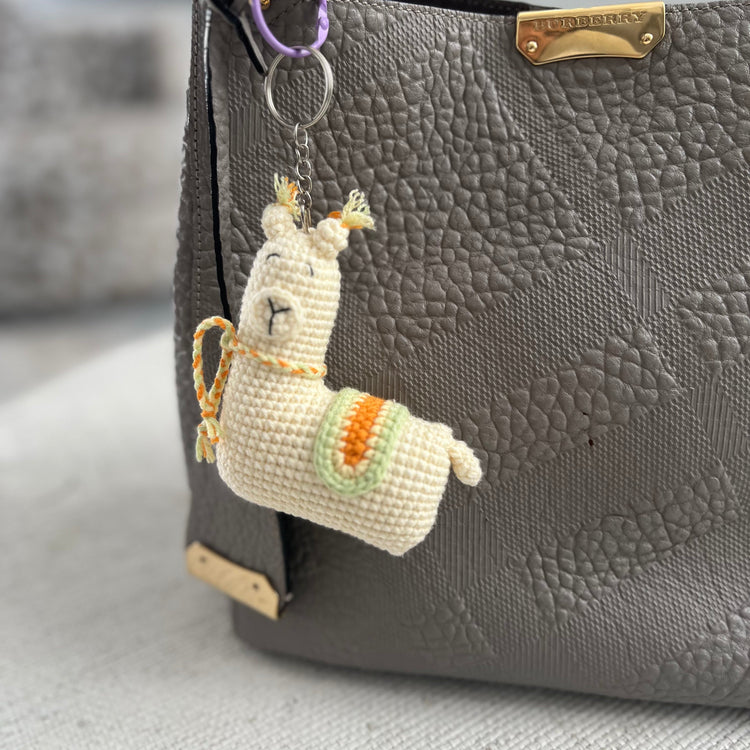Llama-shaped keychain attached to a gray textured handbag.