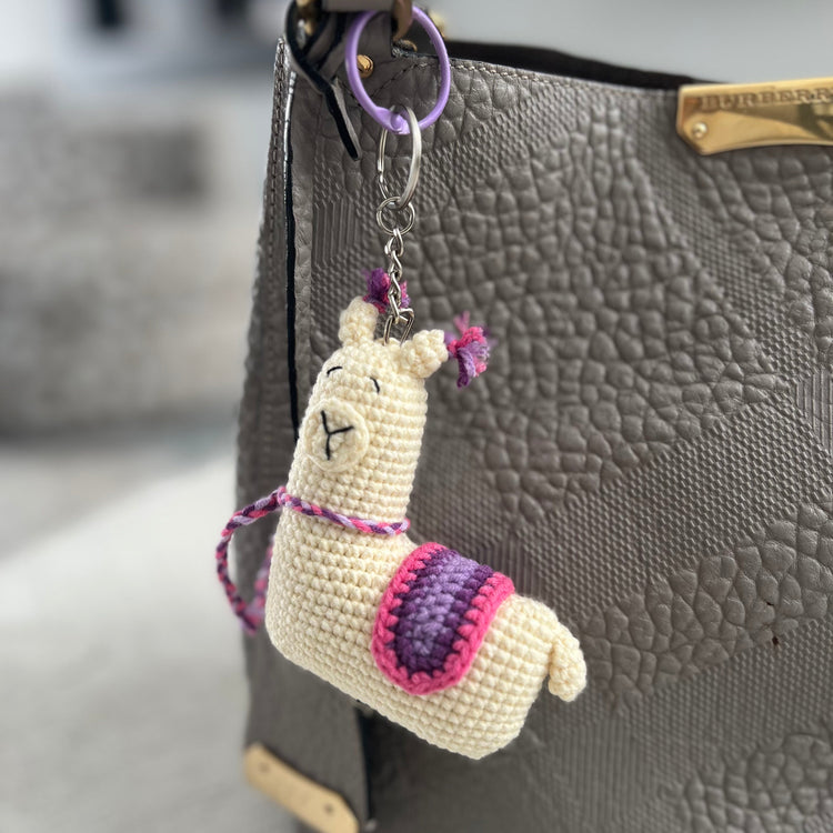 Llama-shaped keychain attached to a gray textured handbag.