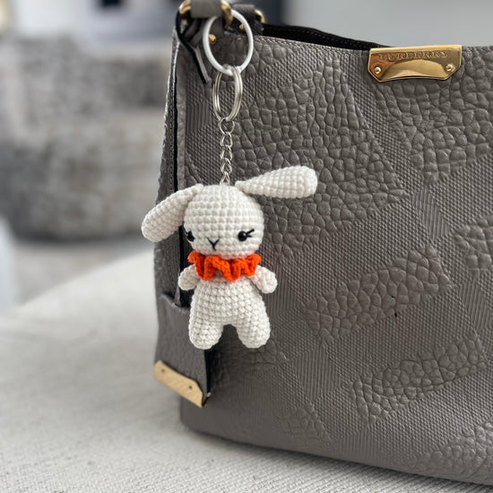 White crocheted bunny bag charm with an orange bow 